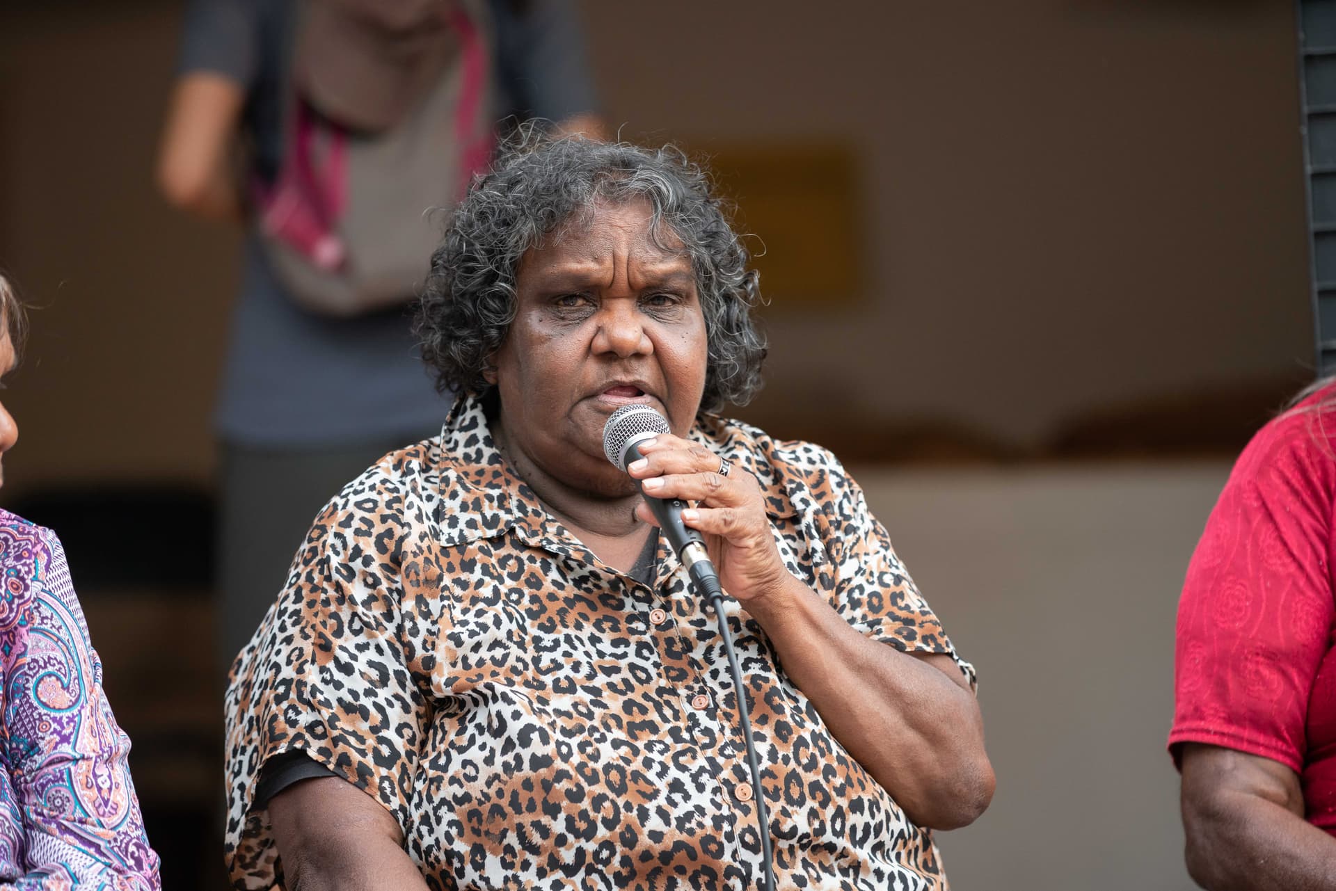 A woman speaking into a microphone during a public gathering.