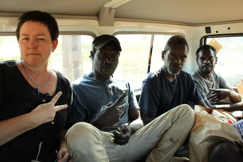 A smiling man seated inside a vehicle during fieldwork travel.