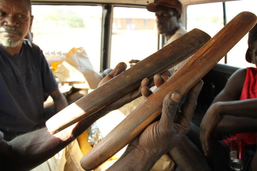 People in a vehicle holding carved wooden objects during a trip.